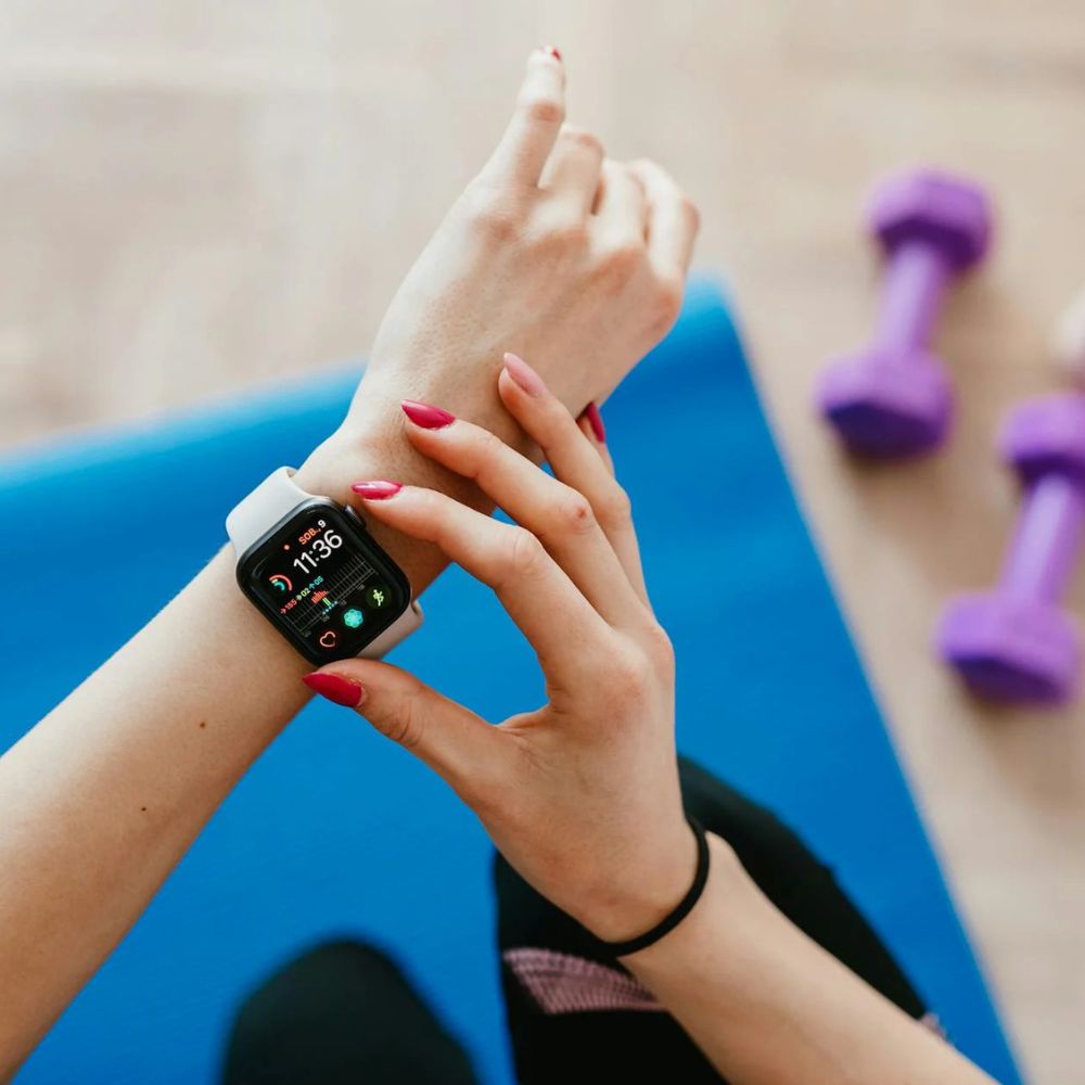 Person using a smartwatch with purple dumbbells in the background
