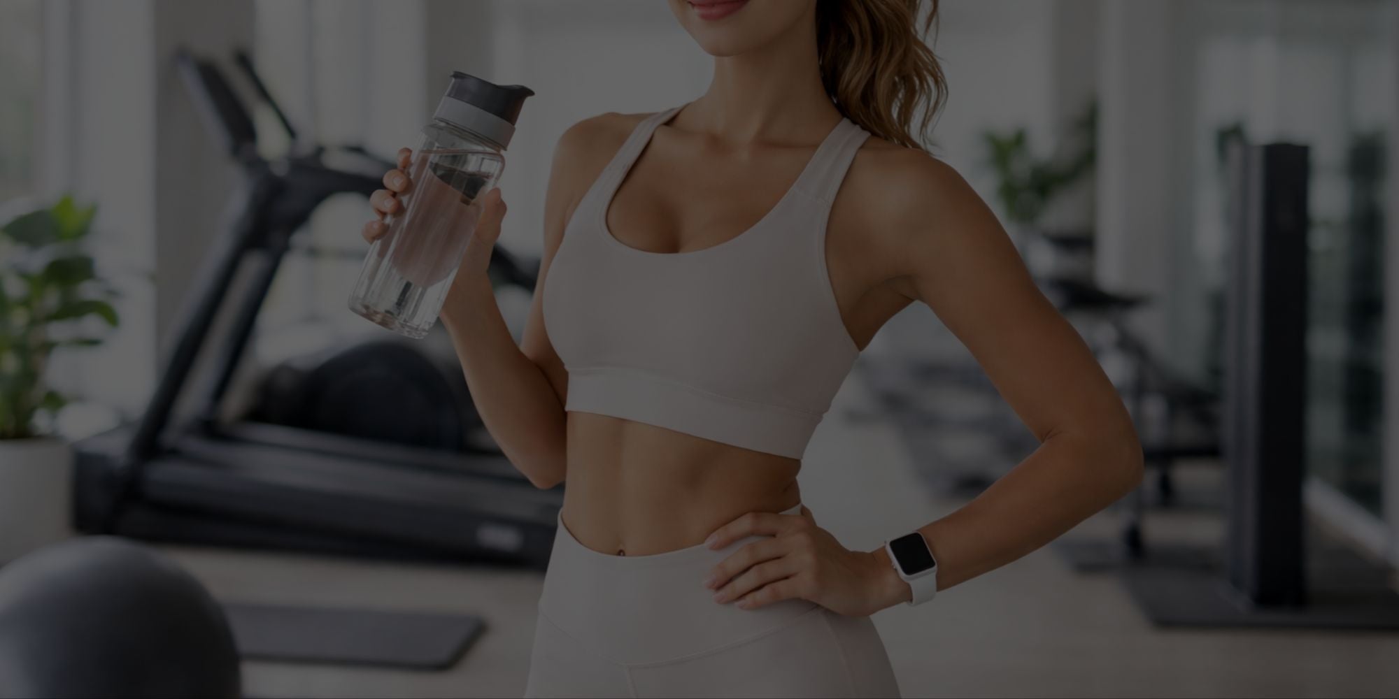 Woman in athletic wear holding a water bottle in a gym setting